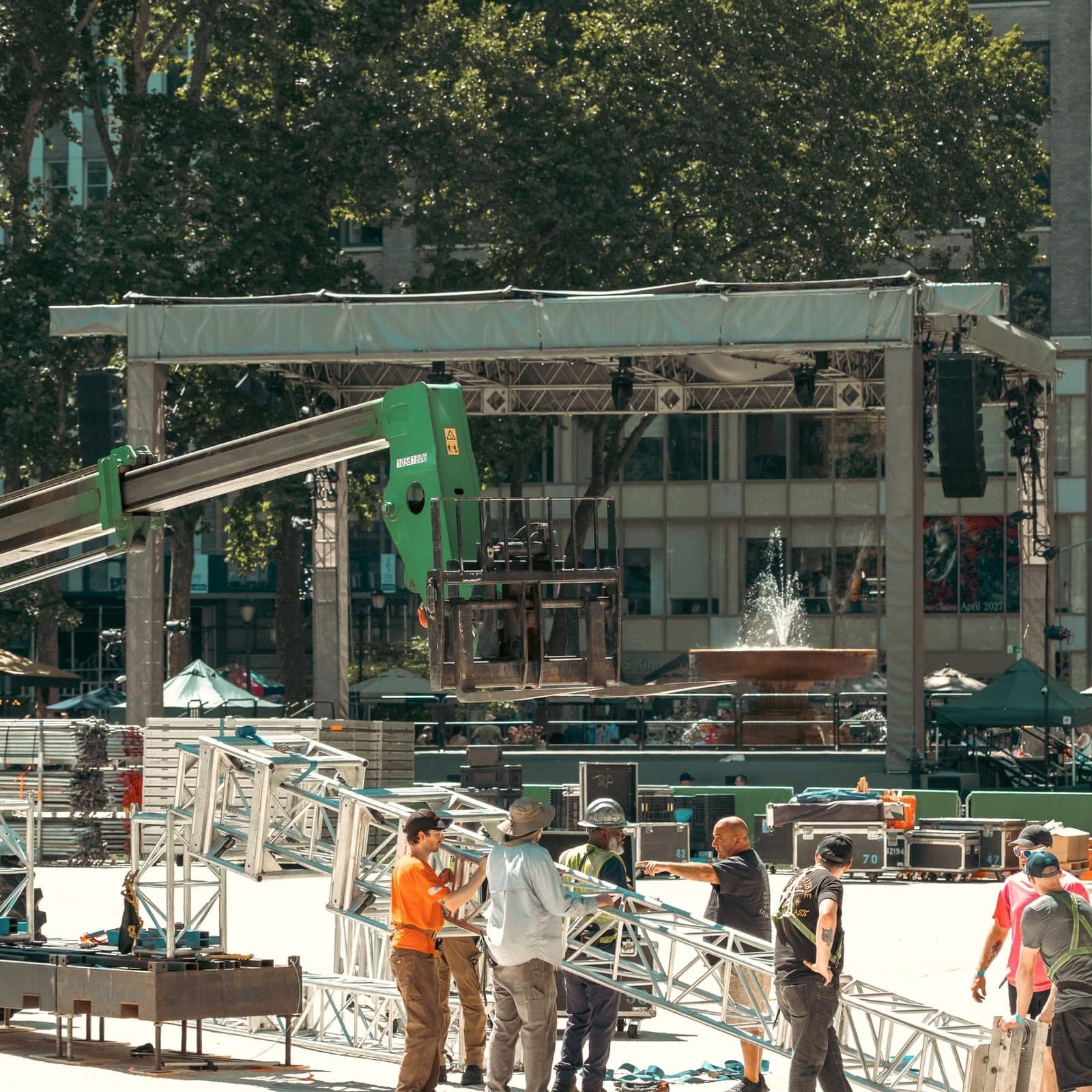 Equipe montando estrutura metálica de palco em praça